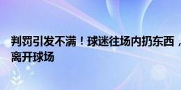 判罚引发不满！球迷往场内扔东西，马宁在安保打伞护送下离开球场